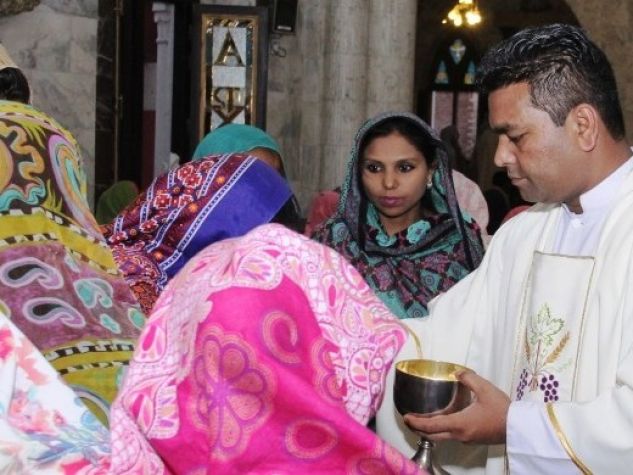 don Iqbal distribuisce l'eucaristia tra i fedeli