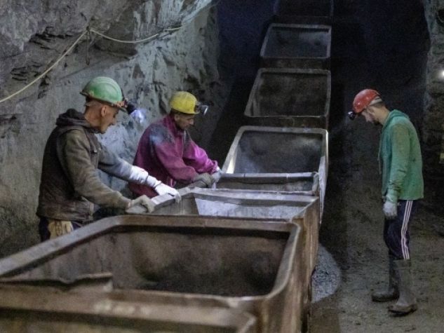 I minatori spingono a mano vecchi carrelli per il trasporto del minerale di cromo nel tunnel della miniera.