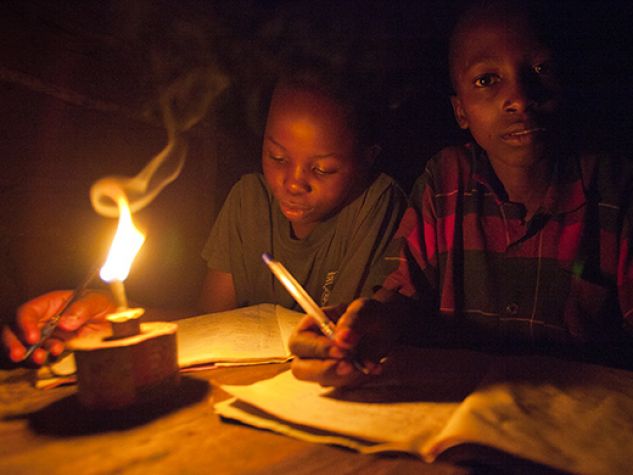 Bambini africani studiano alla fioca luce di una lampada a petrolio