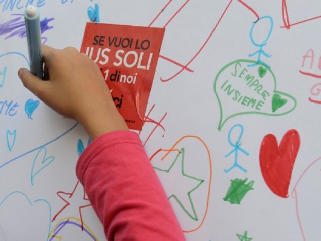 Una bambina scrive un pensiero a favore dello Ius soli nel corso di una manifestazione pubblica
