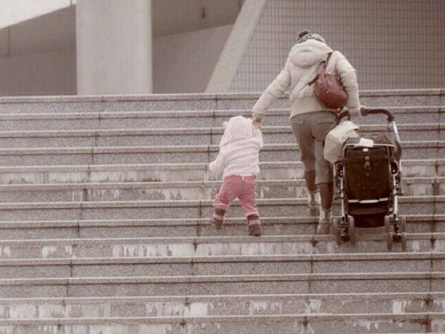 una mamma con bimbo e passeggino sale una scalinata