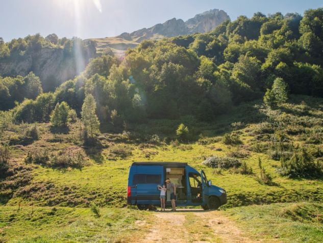 padre e figlia scattano una foto fuori dal loro van in montagna