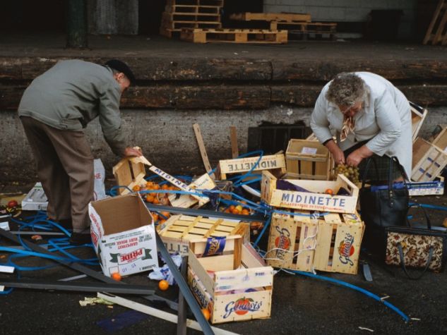Foto di reportorio: persone in situazione di disagio economico cercano tra gli avanzi del mercato frutta e verdura commestibile