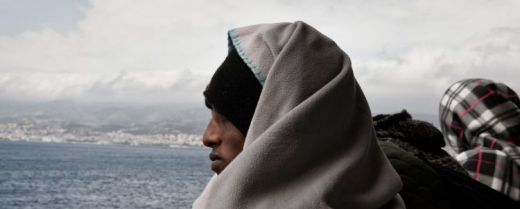 Un migrante scruta l'orizzonte a bordo di una nave.