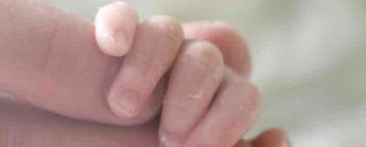 la mano di un neonato stringe la mano di un adulto
