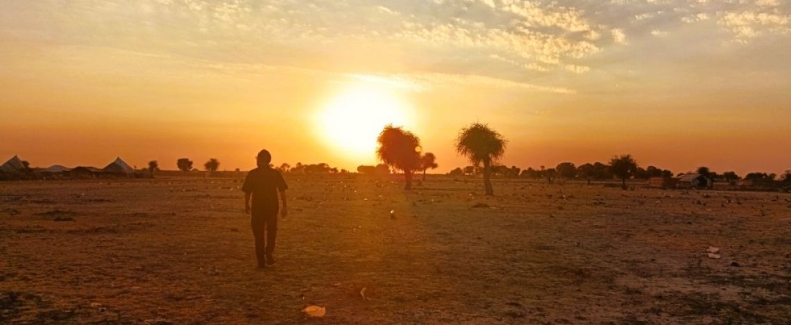 Monsignor Christian Carlassare ritratto sullo sfondo di un tipico paesaggio africano.