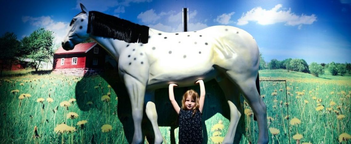 Bambina nei panni di Pippi Calzelunghe che solleva il suo cavallo.