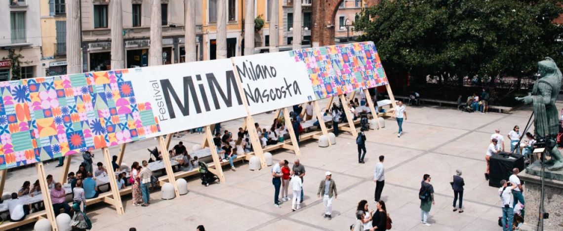 Cartellone del Festival Mim Fiorire a Milano nella piazza delle Colonne di san Lorenzo.