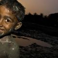 Porto di Chittagong. Due ragazzi giocano con la tipica melma scura, derivata da acque nere e liquami. Il fango, putrido e maleodorante, viene raccolto e utilizzato per la produzione di mattoni. - @Giovanni Mereghetti