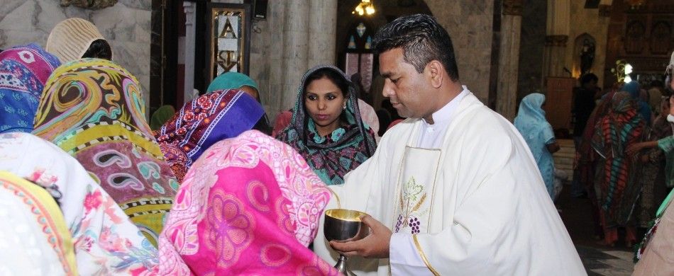 don Iqbal distribuisce l'eucaristia tra i fedeli