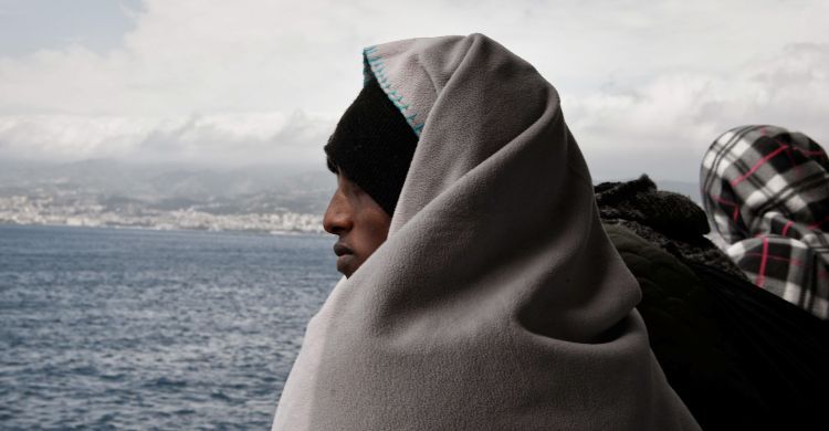 Un migrante scruta l'orizzonte a bordo di una nave.