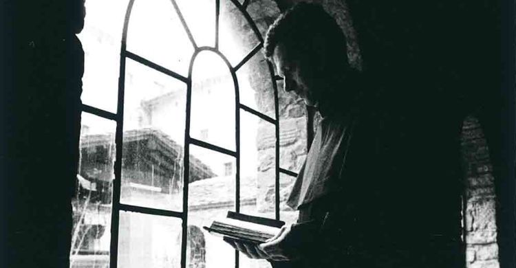 Un frate francescano legge la Bibbia accanto a una finestra, nel Santuario della Verna (AR).