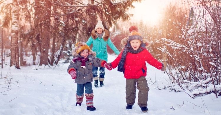 bambini corrono nella neve con la mamma