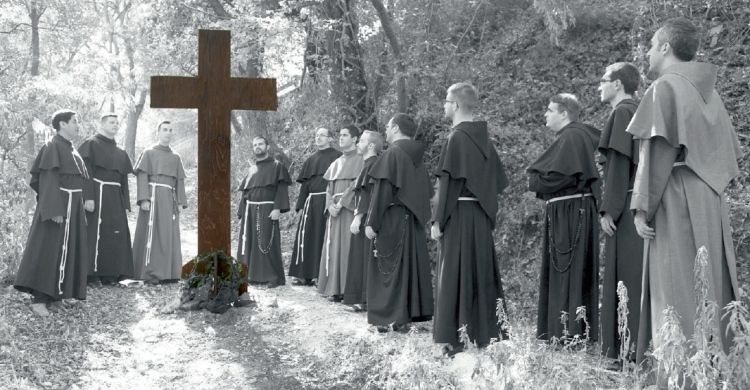 gruppo di giovani frati davanti a un crocifisso